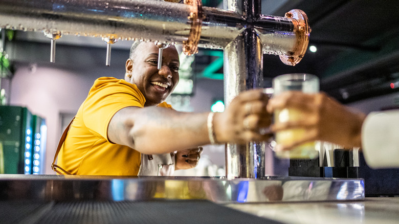 A bartender serving a patron beers