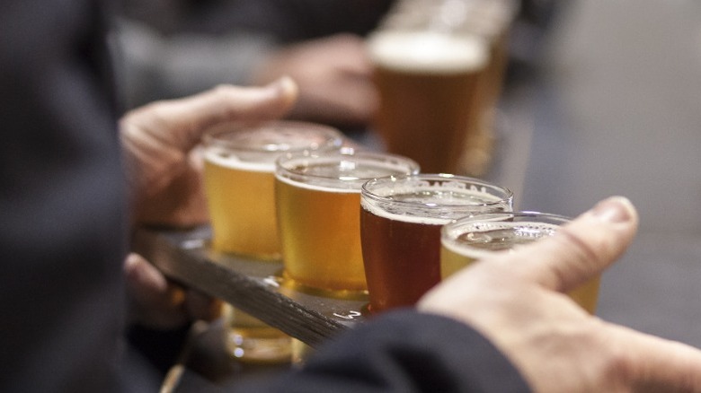 A person holding a flight of beers