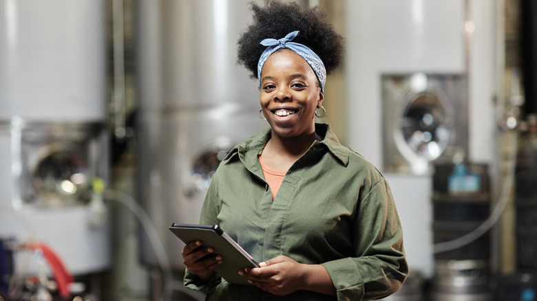 A smiling brewery employee in the back of a brewery
