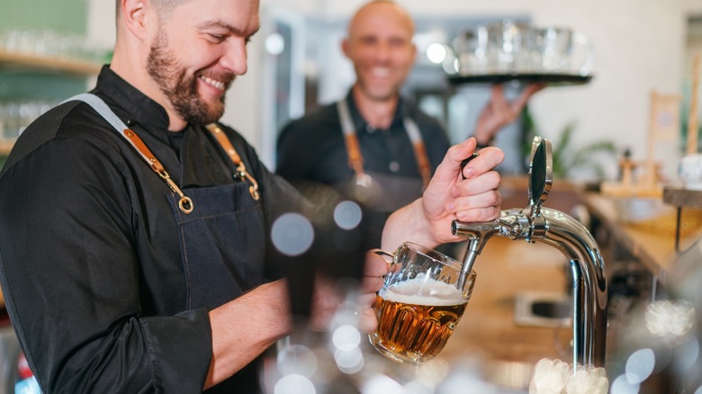 A brewery employee smiling as he fills a draught beer