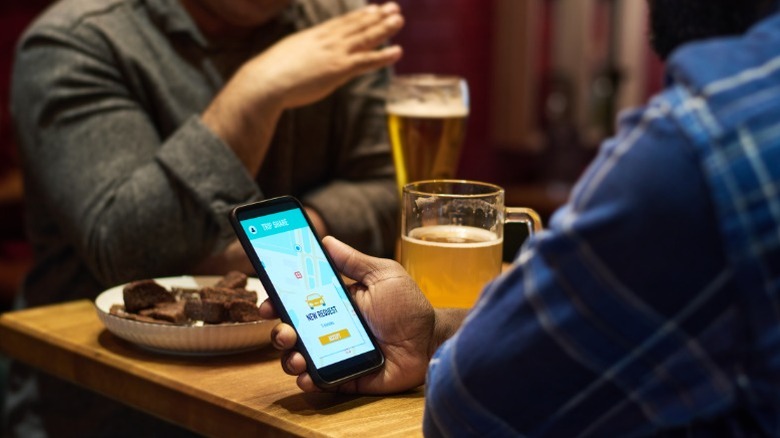 A person checking their phone while drinking a beer