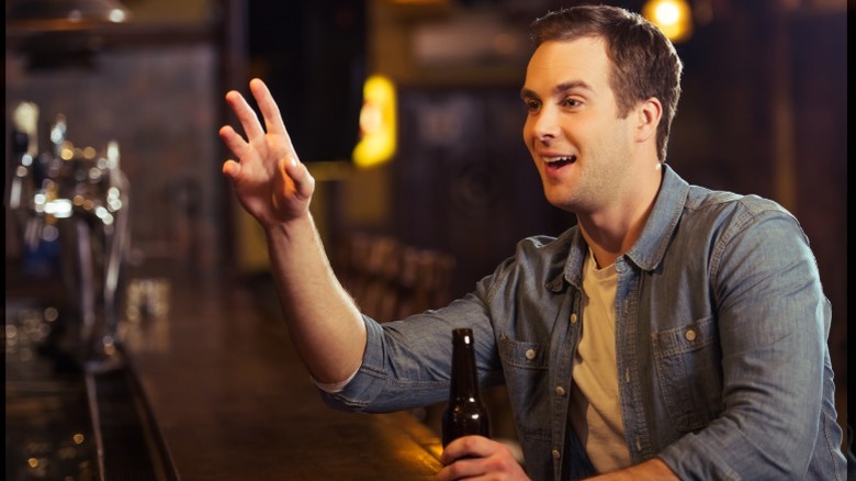 A young man ordering a beer at a bar