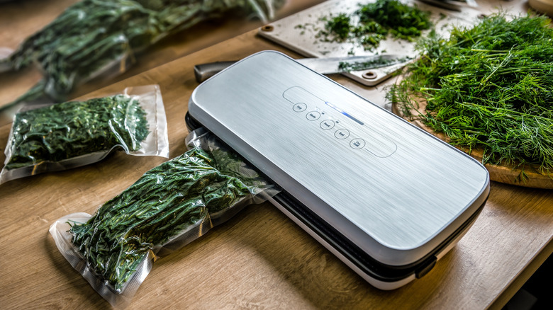 A vacuum sealer wrapping parcels of fresh dill