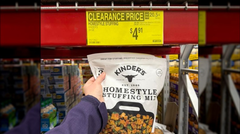 A hand holds a bag of stuffing mix in front of a clearance sign at Sam's Club