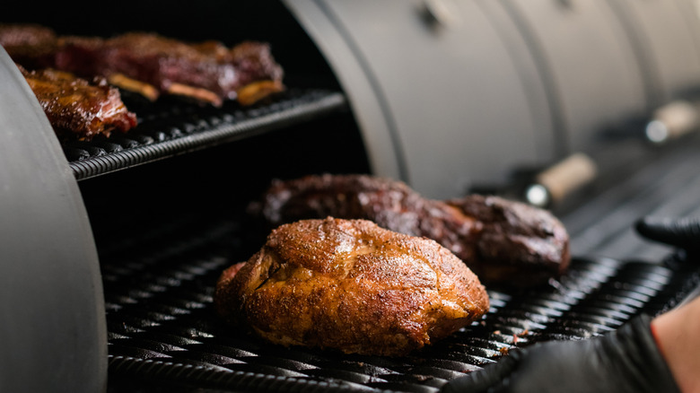Hands pulling meat out of a smoker