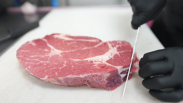 Hands trimming a piece of steak