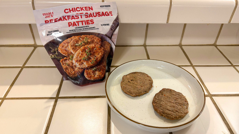 A package of chicken patties next to a plate with two patties against a white tile countertop