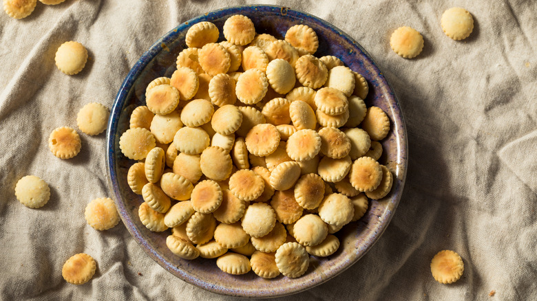 A bowl of oyster crackers on a tan linen tablecloth