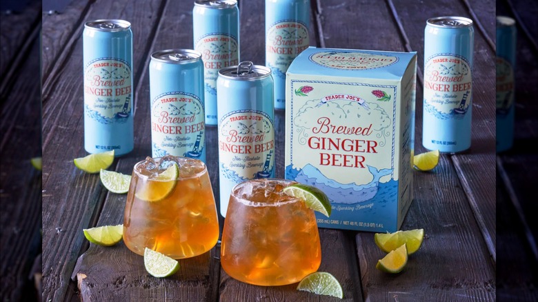 Blue cans of Trader Joe's Brewed Ginger Beer, some poured into stemless wine glasses