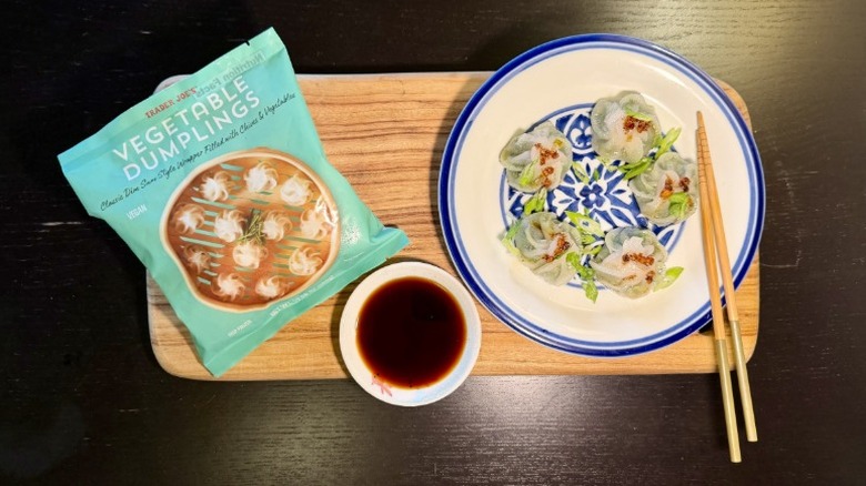 Trader Joe's Vegetable Dumplings on a plate next to their packaging, a bowl of soy sauce, and chopsticks