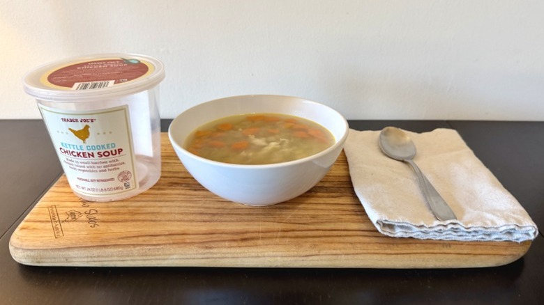 Trader Joe's Kettle Cooked Chicken Soup on a wooden cutting board next to spoon on a napkin