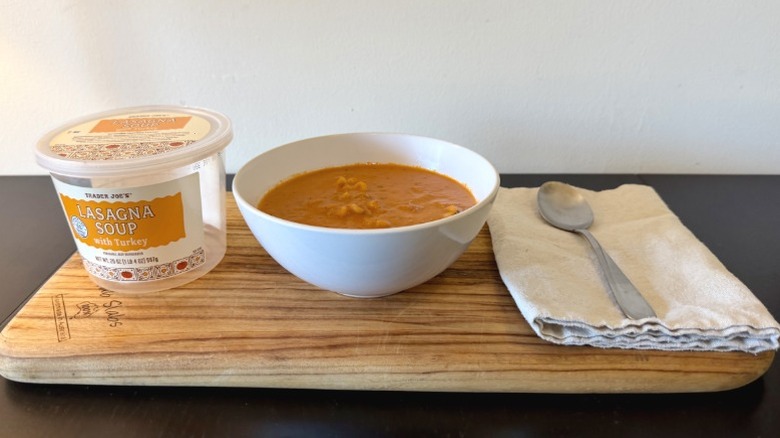 Trader Joe's Lasagna Soup on a wooden cutting board next to spoon on a napkin