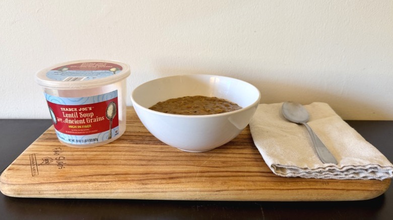 Trader Joe's Lentil Soup with Ancient Grains on a wooden cutting board next to spoon on a napkin