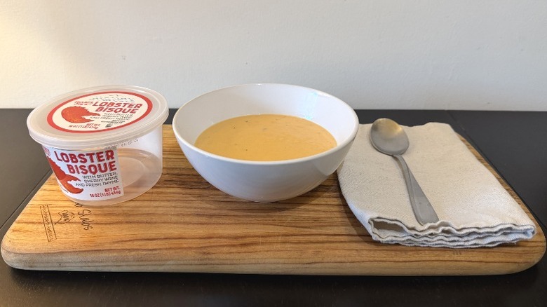 Trader Joe's Lobster Bisque on a wooden cutting board next to spoon on a napkin