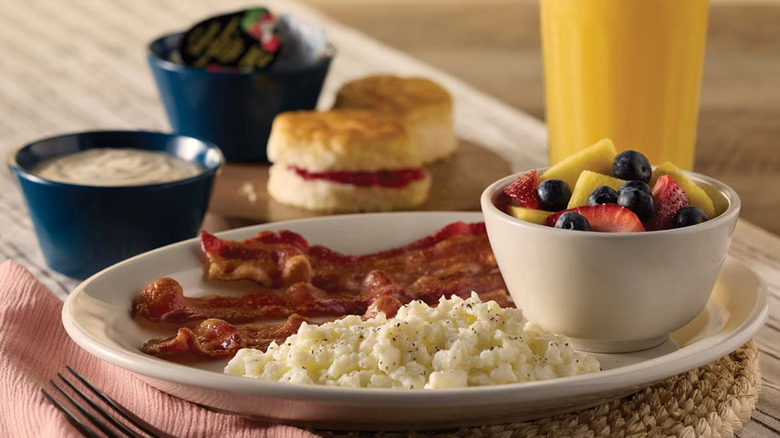 Cracker Barrel country breakfast with grits, bacon, fruit, biscuits, and orange juice