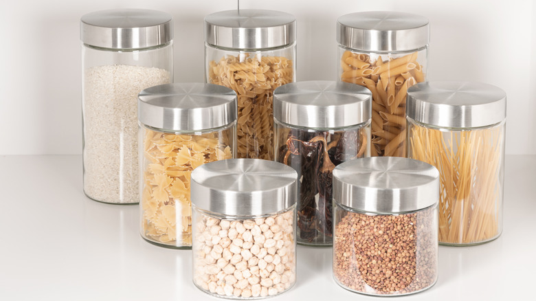 An array of lidded glass jars holding dried beans, dried pasta, and other pantry staples