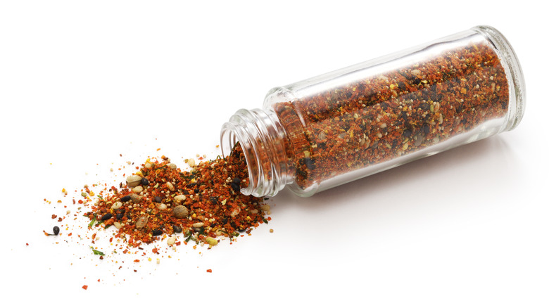 A spice jar with a mix of different spices turned on its side and spilling