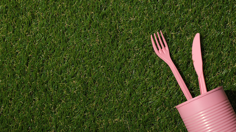 A painted pink tin can with a plastic fork and knife sticking out of the top