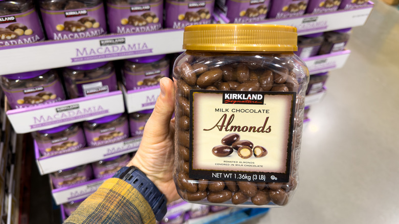 Hand holding jar of Kirkland Signature milk chocolate almonds