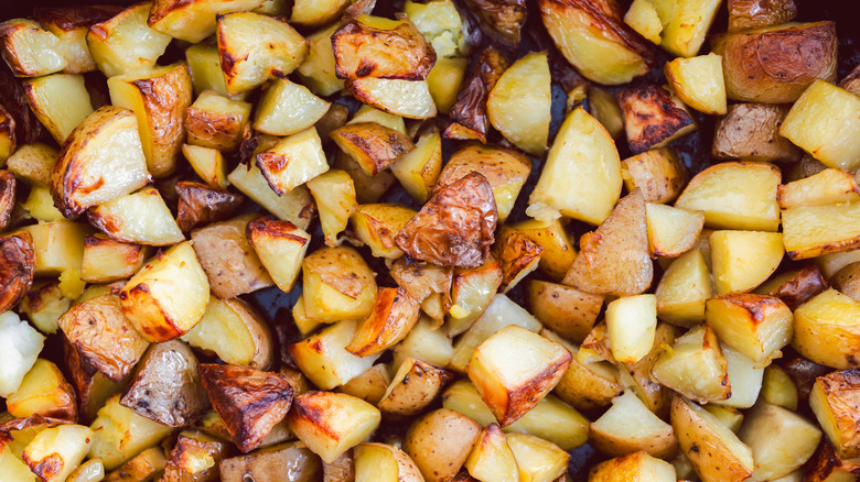 Close up of many roasted potatoes together on a baking sheet