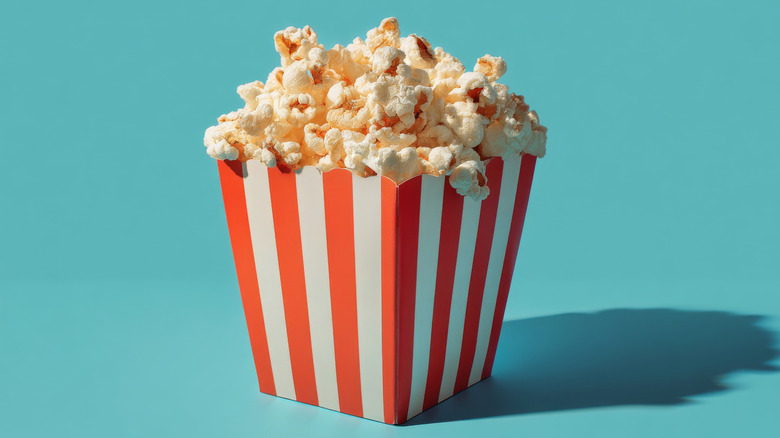 A red and white bucket of popcorn isolated against a bright blue background