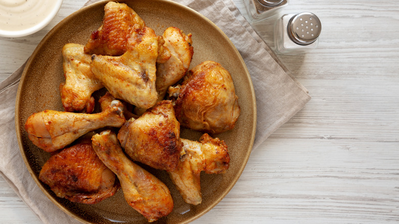 Close up of fried chicken wings on a brown plate atop a cloth napkin