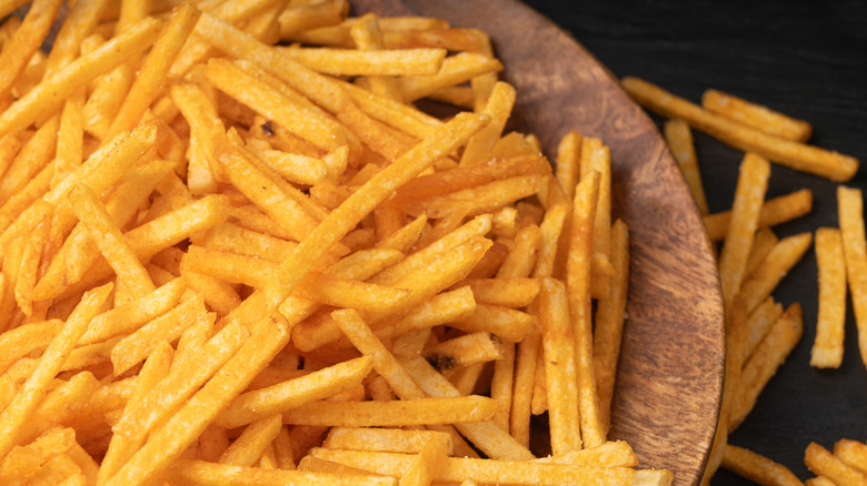 Close up of crispy golden French fries on a wooden surface