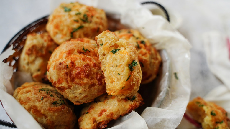 Close up of a basket of cheddar cheese biscuits sprinkled with parsley
