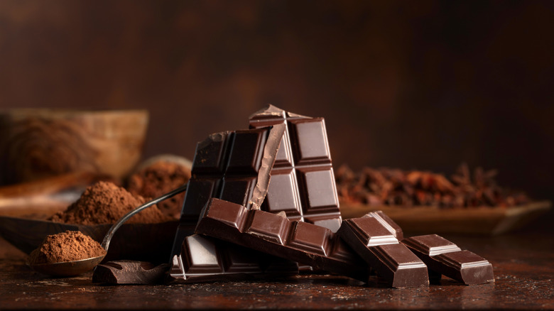 A pile of broken chocolate and cocoa in the background against a brown backdrop