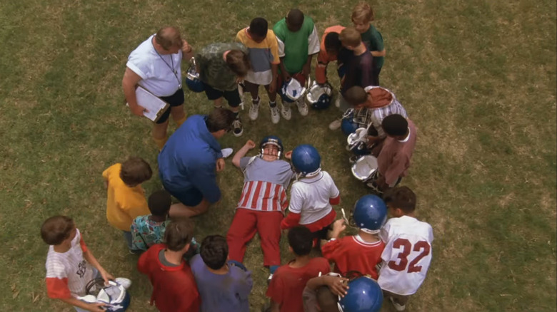 Little Giants cast in circle around collapsed kid in field