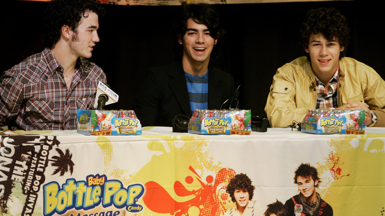 The Jonas Brothers on a stage promoting Baby Bottle Pops