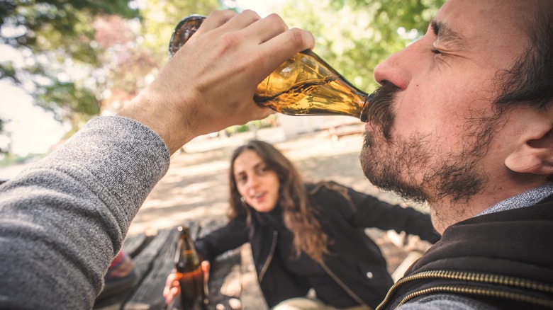 man chugging beer outdoors
