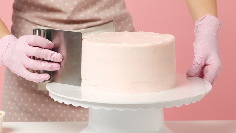 Person smoothing a cake's frosting