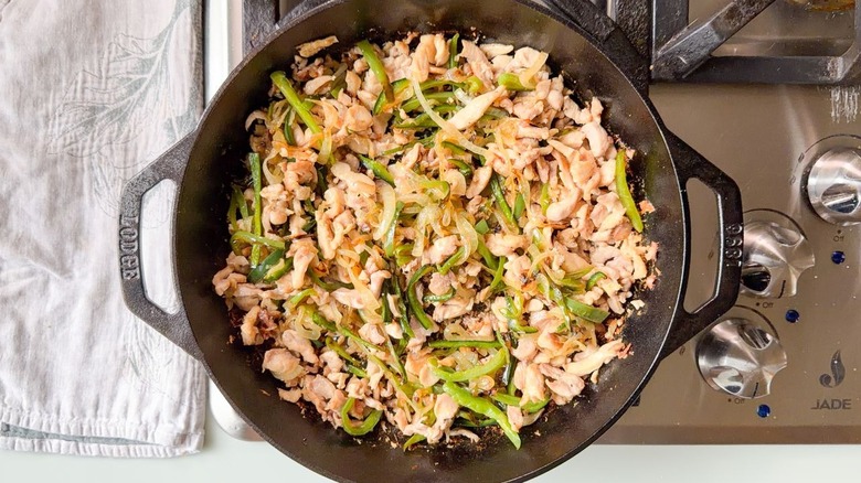 Sauteed chopped chicken thighs, poblano peppers, and sweet onions in cast iron skillet