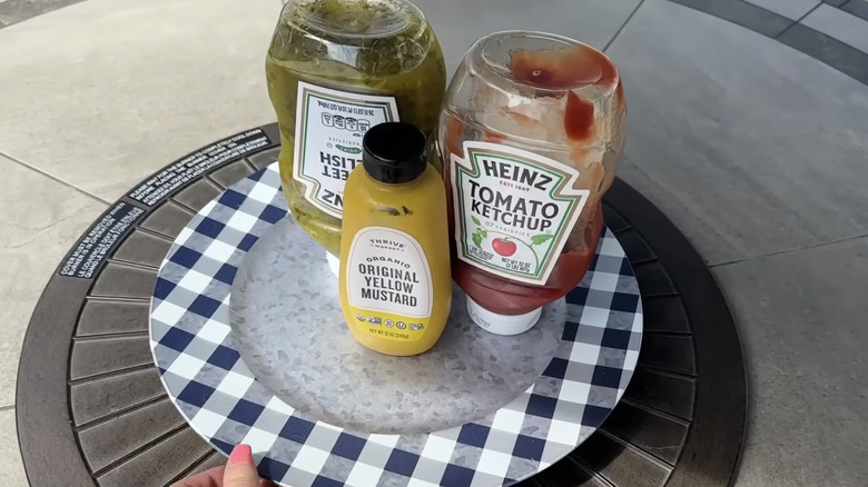 A woman's hand holding a checkered plate with condiments on it