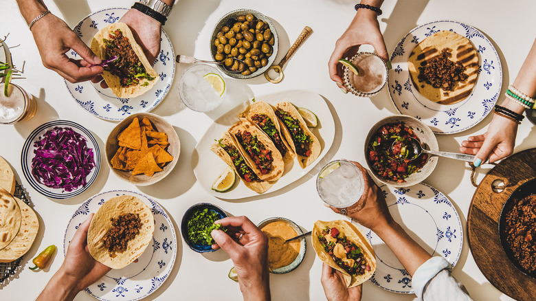 hands making tacos over table