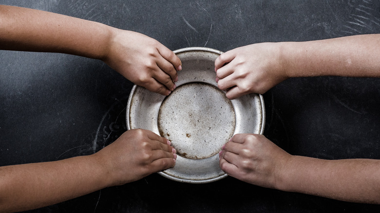 Empty food bowl held by two children's hands