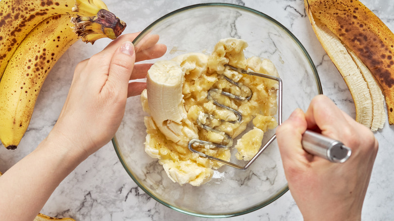 hands mashing bananas in bowl