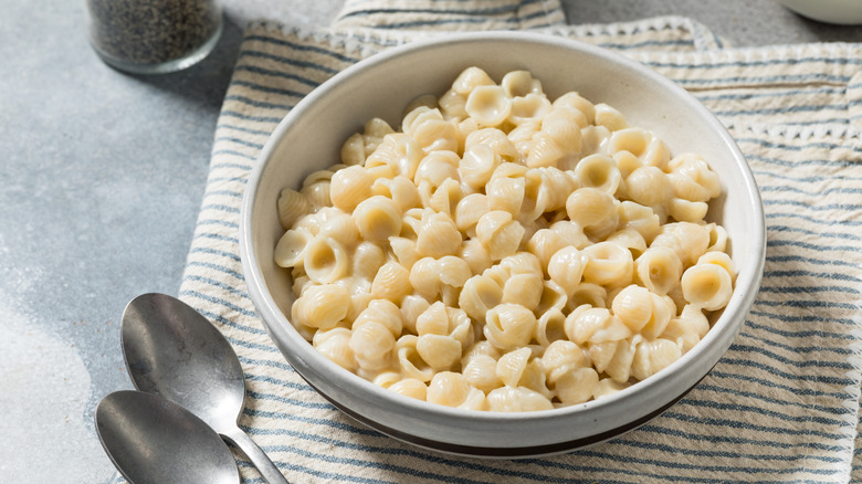 Bowl of mac and cheese next to two spoons on a place mat