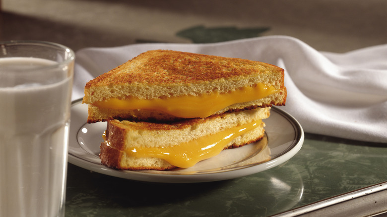classic grilled cheese sandwich on plate with milk