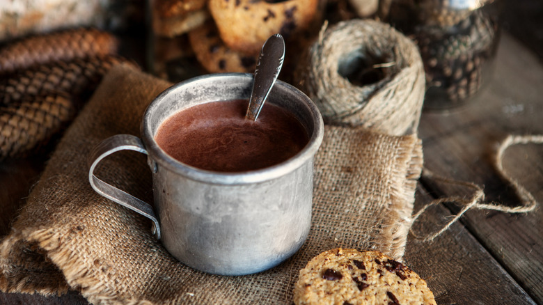 a metal cup of hot chocolate on a burlap sack