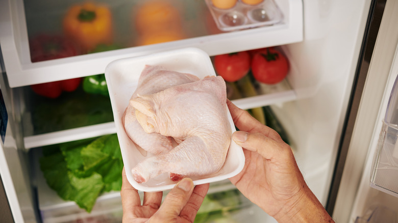 Man removes chicken from fridge