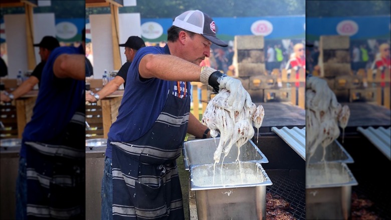 barbecue chicken being dunked in white barbecue sauce