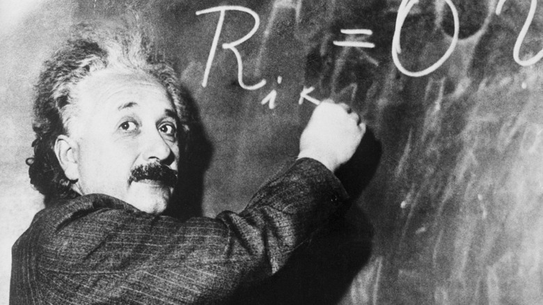 Albert Einstein writing equation on chalkboard