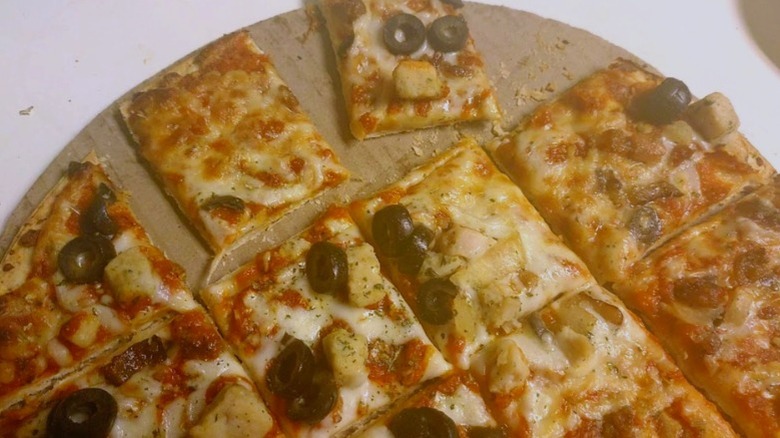 Mama Cozzi's Supreme Bloody Mary-Style Pizza sliced into squares sitting on a cardboard disc on a kitchen counter
