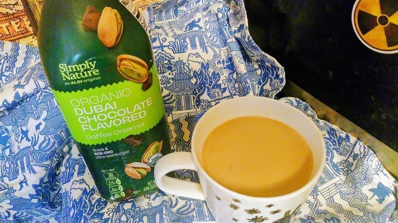 bottle of Simply Nature Organic Dubai Chocolate Flavored Creamer next to coffee in a white mug with a red maple leaf
