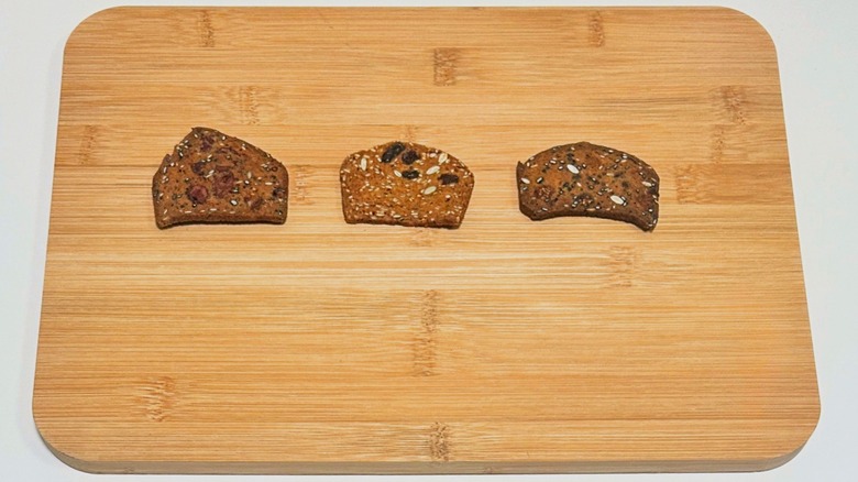 Three Savoritz Artisan Crisps arranged in a line on a wood cutting board