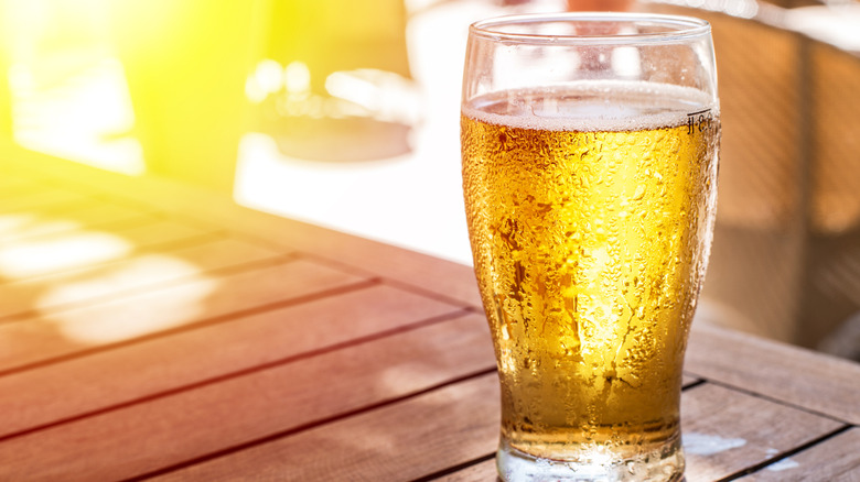 A cold glass of beer, outdoors in the sunlight