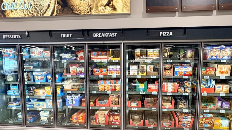 The freezer section of an Aldi with desserts, breakfast, pizza, and fruit and a sign above that says "Chill Out"