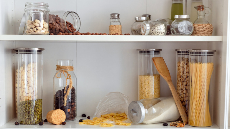 Kitchen shelves with various dried items, in a cluttered state